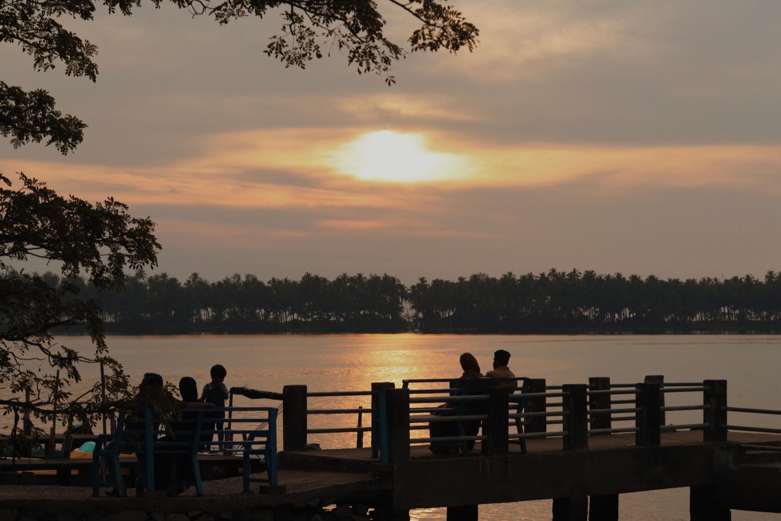A peaceful sunset scene with silhouettes by a lake, creating a warm and serene atmosphere.